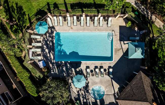 a birds eye view of a pool and patio with umbrellas and tables