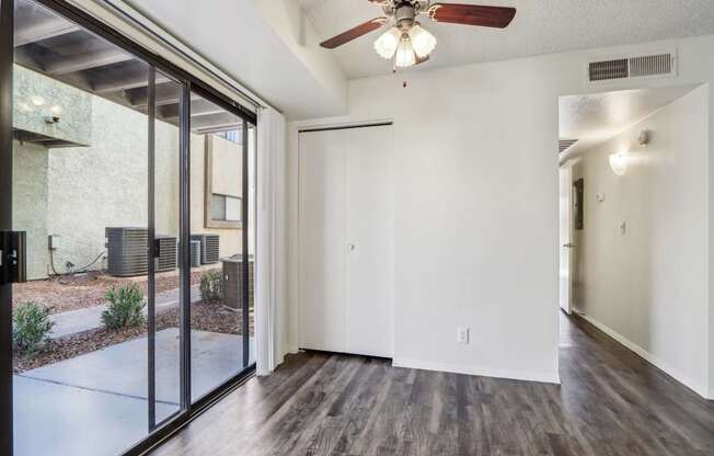 A room with a ceiling fan and sliding glass doors.