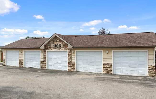 a brick garage with white doors and a sign on the roof