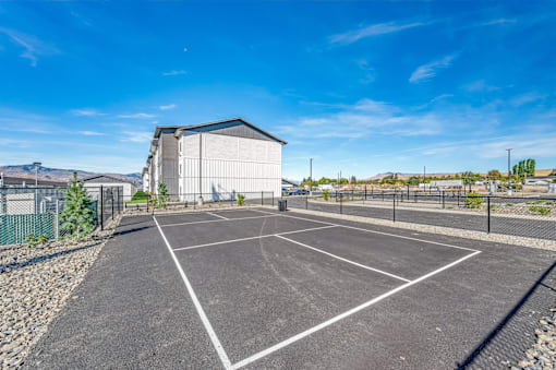 an empty parking lot with a building in the background at Gateway Apartments, East Wenatchee ,Washington, 98802