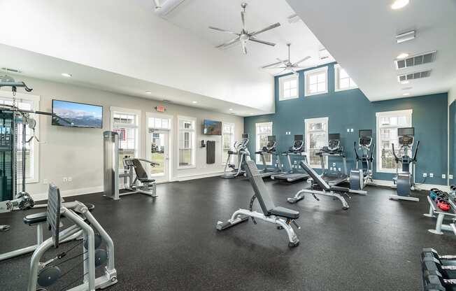 A spacious gym with a variety of equipment and a flat screen TV mounted on the wall.