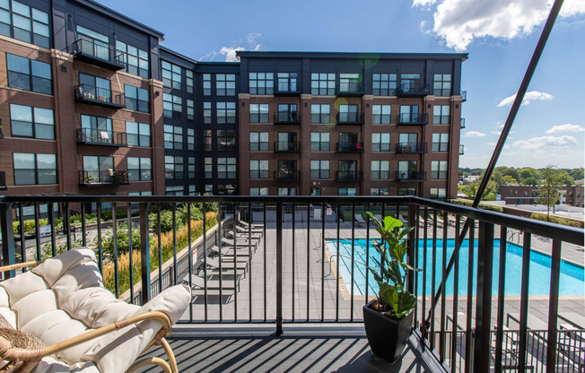 a balcony with a couch and a potted plant and a pool in the background