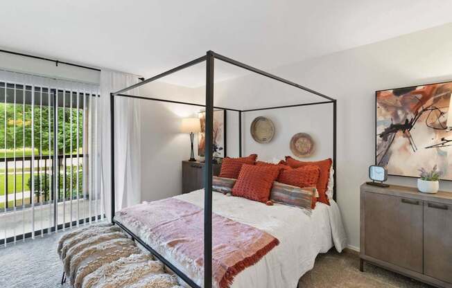 A bedroom with a four poster bed and a painting on the wall.