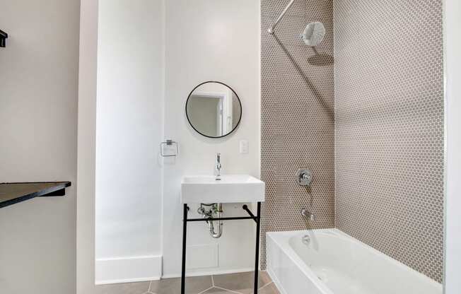 a small bathroom with a sink and a tub and a mirror