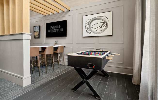 A pool table is in the middle of a room with a bar and chairs.