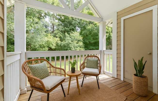 A white chair with a green pillow sits on a porch.