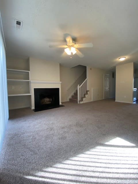 a living room with a ceiling fan and a fireplace