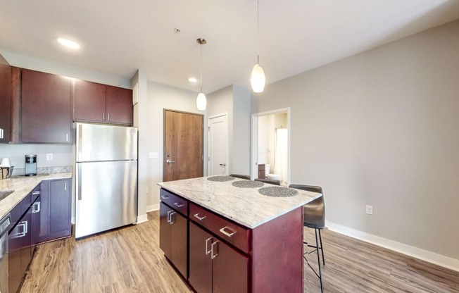 a kitchen with a marble counter top and a stainless steel refrigerator