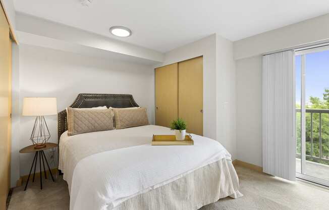 a bedroom with a bed and a sliding glass door with window coverings at Villaggio Apartment Homes, Washington, 98402