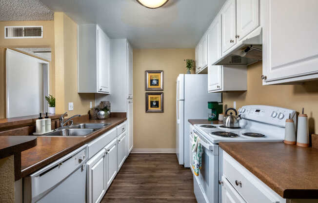 A kitchen with white cabinets and a fridge.