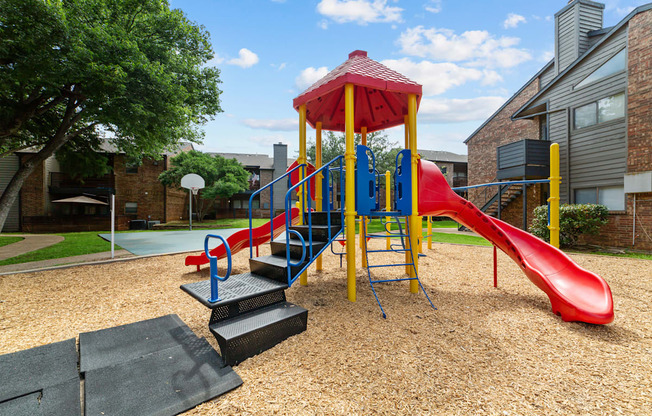 A playground with a red slide and a yellow and blue structure.