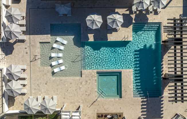 an aerial view of a pool and umbrellas on the side of a building