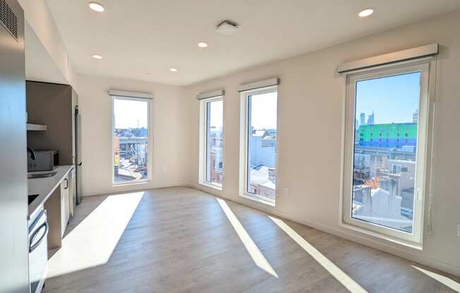 an empty living room with large windows and a city view