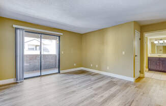 an empty living room with a sliding glass door to a patio