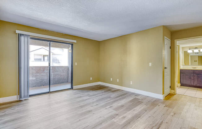 an empty living room with a sliding glass door to a patio