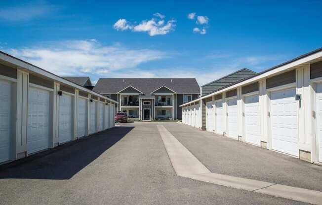 a row of garages with white doors and a house in the background at Madison Park, Bozeman, MT, 59718