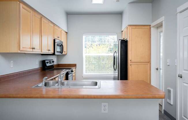 A kitchen with wooden cabinets and a black refrigerator.