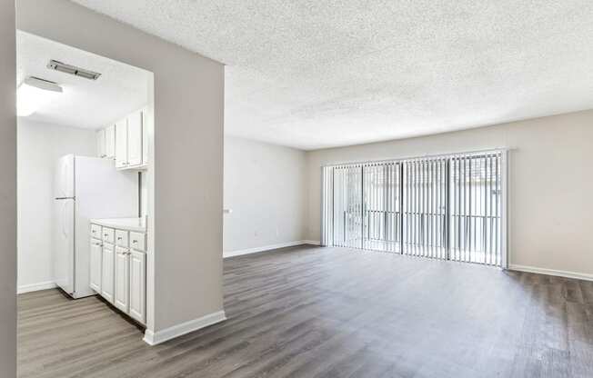 an empty living room and kitchen with a large window