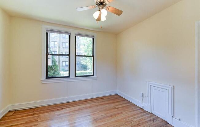 vacant bedroom with hardwood floorings, large windows and ceiling fan at the klingle apartments in washignton dc