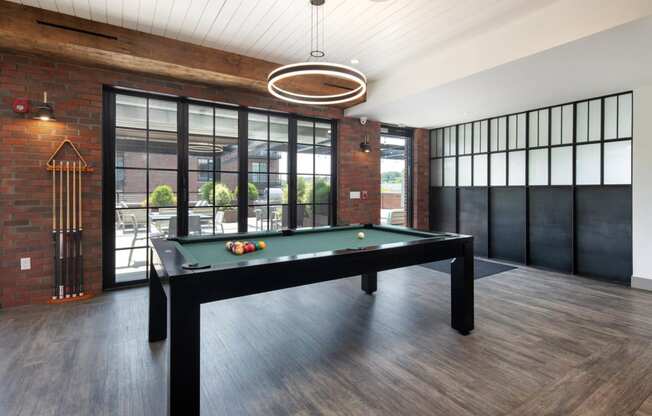 a pool table in a living room with a brick wall