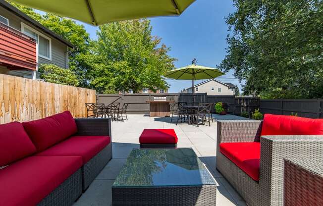 a backyard patio with red couches and a glass table at Quartz Creek, Mountlake Terrace, WA, 98043