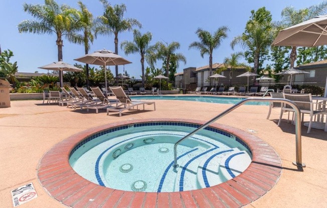 a hot tub in a pool with chairs and umbrellas