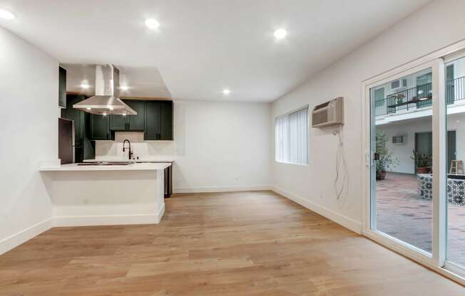 a living room with a kitchen and a large glass door