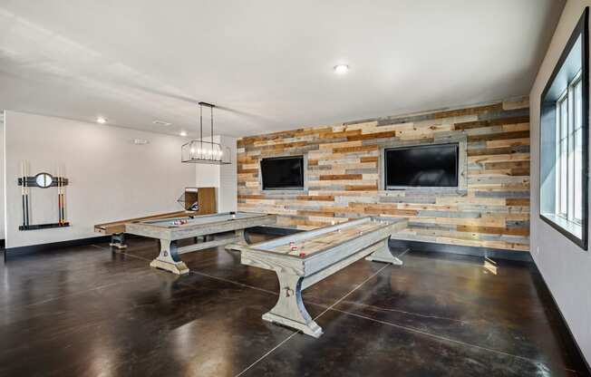 a game room with two pool tables and two televisions