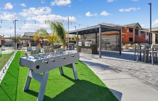 A foosball table is in the middle of a grassy area.