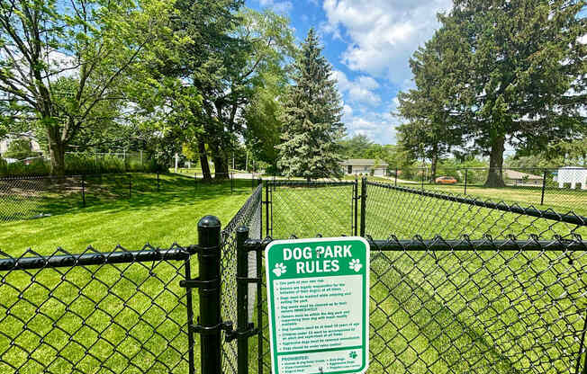 A sign on a fence that says Dog Park Rules.