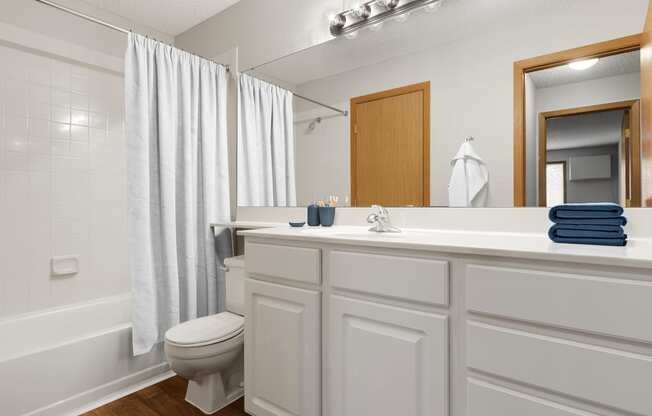 a bathroom with a white shower curtain and a white toilet next to a white bathtub