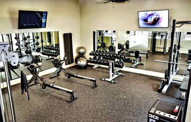 A gym with a variety of equipment including dumbbells, weight plates, and a bench press.at Carson Street Towers, Overland Park, 66223