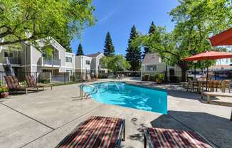 Pool Area with Trees, Red/White/Black Lines Runing Down Lounge Chairs and Apartment Exteriors