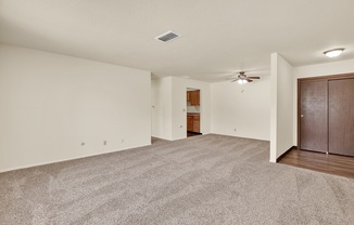 A spacious room with a ceiling fan and carpeted floor.