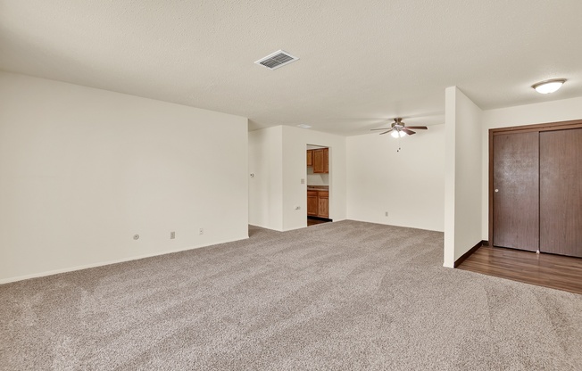 A spacious room with a ceiling fan and carpeted floor.