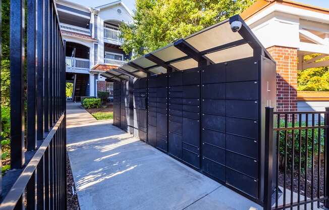 the gate to the driveway of an apartment building with a black fence