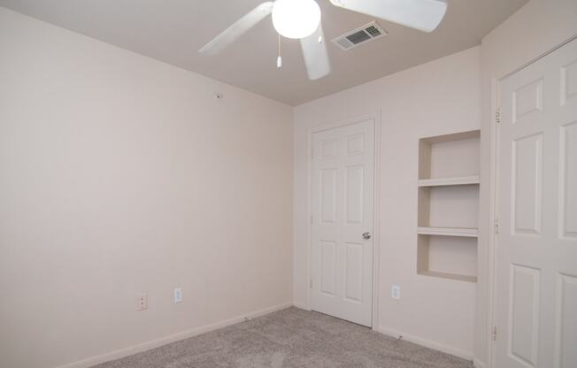 an empty bedroom with a ceiling fan and a closet