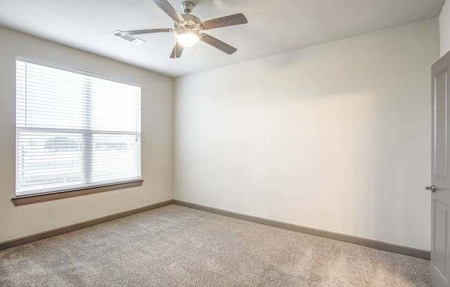 an empty room with a ceiling fan and a window