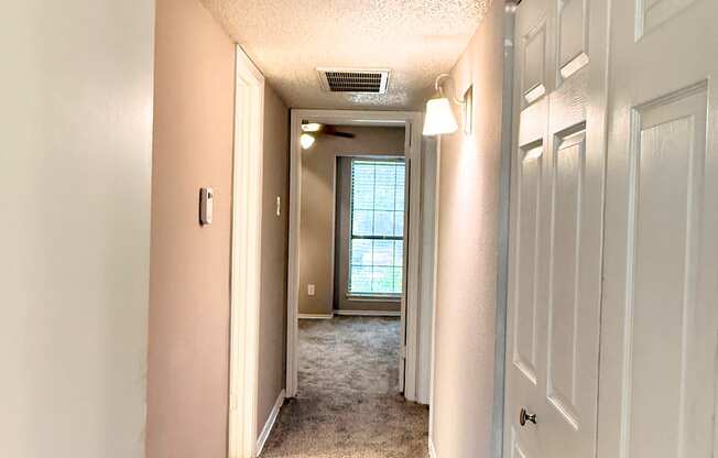 A hallway with white doors and carpeted floor.