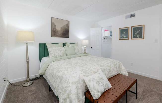 A bedroom with a bed, lamp, and pictures on the wall.