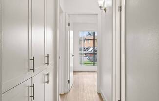 A long hallway with white doors and a light on the wall.
