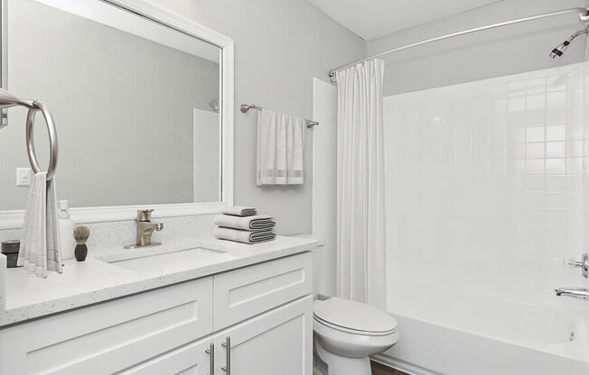 Model Bathroom with White Cabinets, Wood-Style Flooring and Shower/Tub at Grand Pavilion Apartments in Tampa, FL.