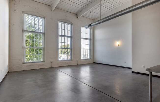 an empty room with three large windows and a table at Highland Mill Lofts, Charlotte, NC
