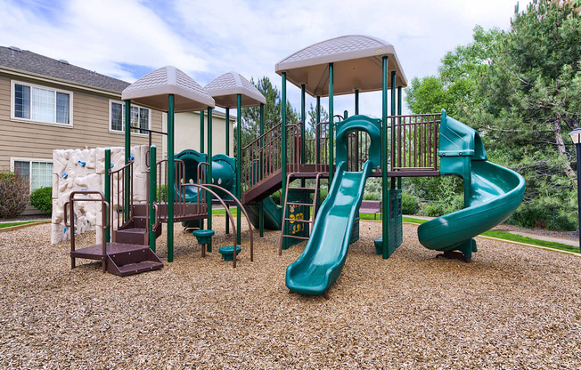 A playground with a green slide and a brown and green play structure.