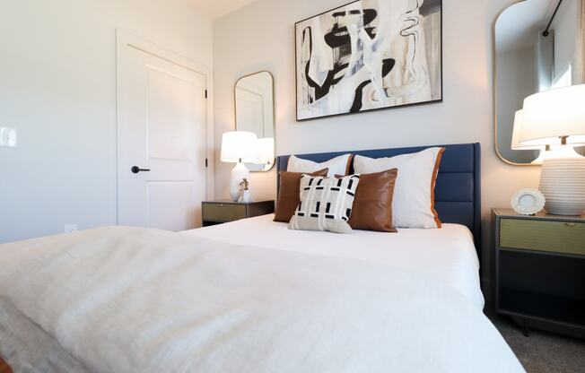a bedroom with a bed and two lamps and a painting on the wall
