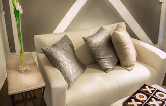 Brookmore apartments Pasadena - Modern Cream Sofa with grey and cream throw pillows, End Table with tall flower vase, and Hardwood-Inspired Flooring in living room sofa area