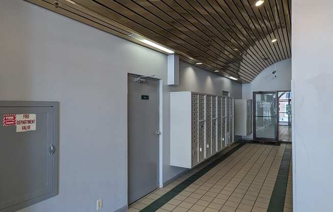 a hallway with white walls and a wood ceiling with lights and doors
