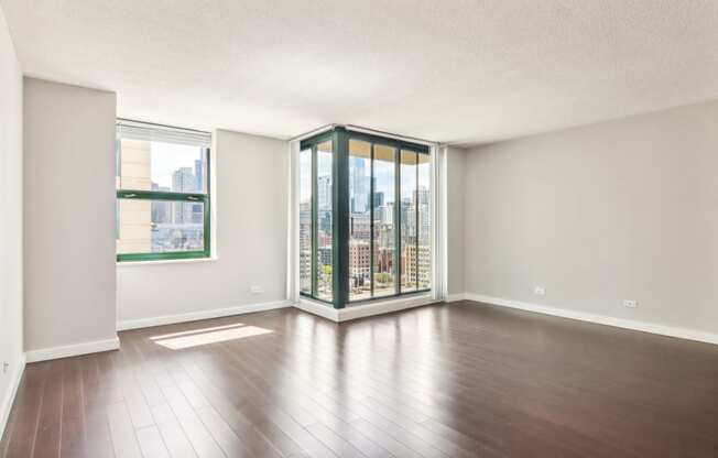 an empty living room with hardwood floors and a large window