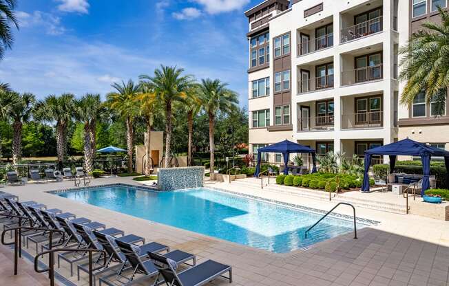 a swimming pool with lounge chairs in front of a building