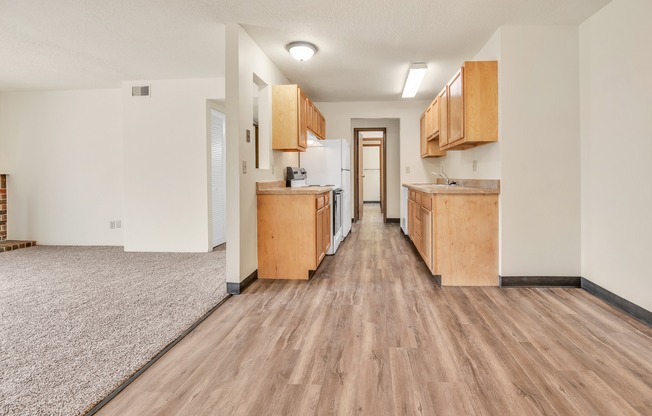 A long, narrow apartment with wood floors and cabinets.